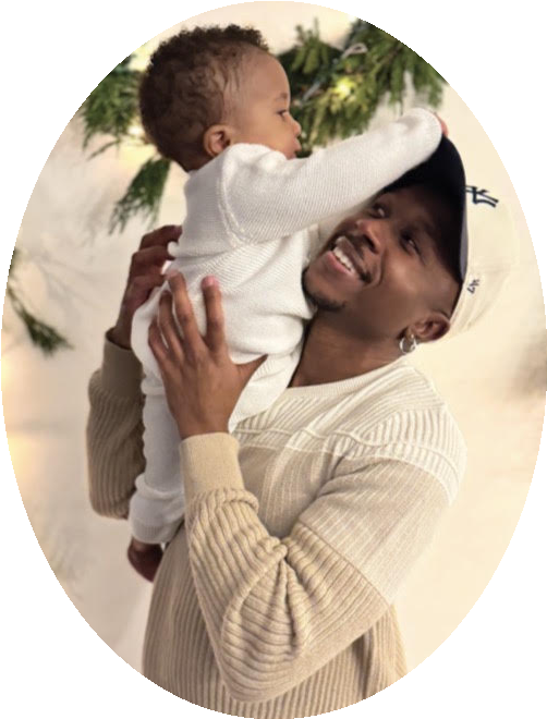 Xavier Brodie smiling as he lifts baby Amir into the air